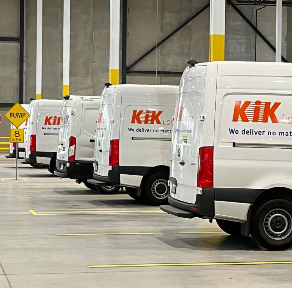 A row of white vans parked in a warehouse.